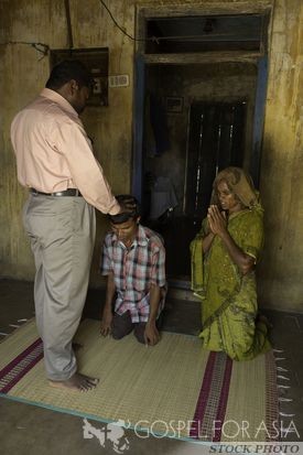 pastor praying for young boy - Gospel for Asia - KP Yohannan