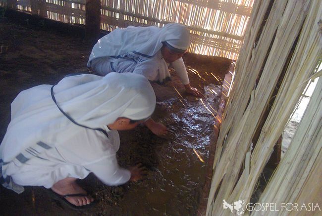 Sisters of Compassion fixing a widow's mud floor.