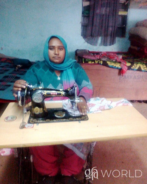 Woman with sewing machine she received from gfa partners.