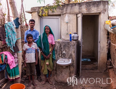 Family stands in front of a toilet that was given to them.