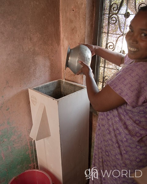Woman using a BioSand water filter provided to her through GFA World.