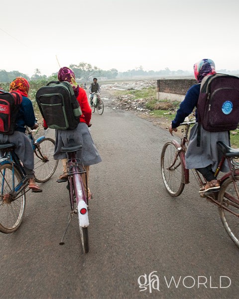 Girls in GFA World's child sponsorship program ride bikes down the road.