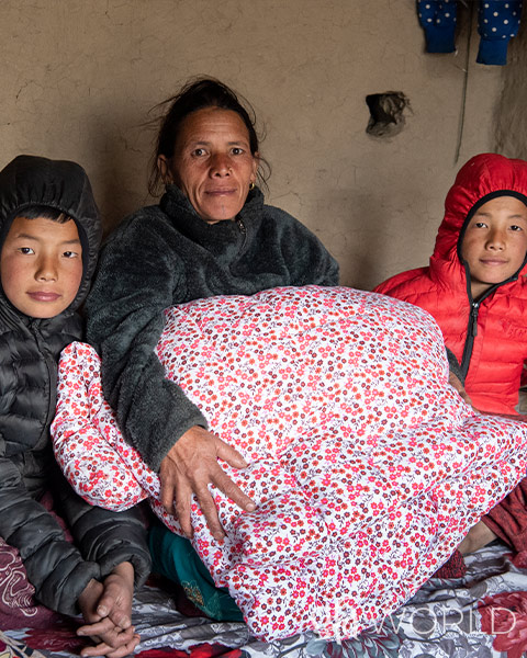 Woman and her sons pictured with a blanket they received from GFA World.