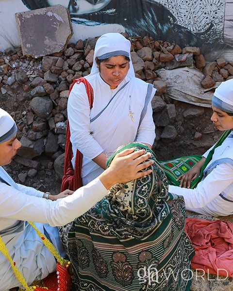 Sisters of Compassion pray over a woman.