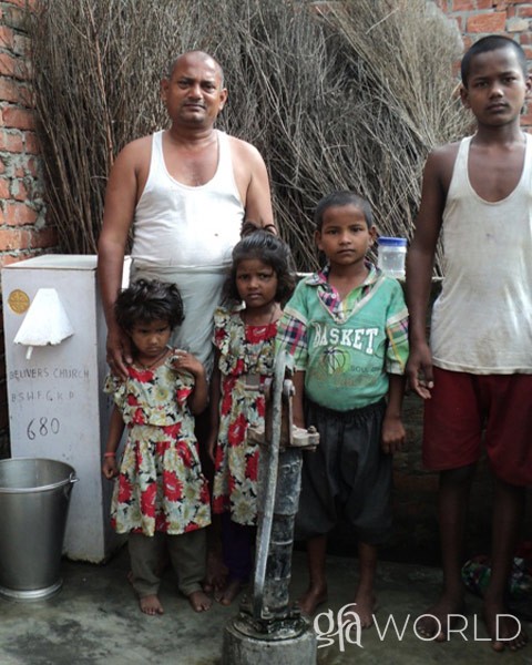 Man and his family stand beside the GFA World Biosand water filter.